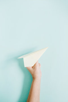 Women Hand Holding Paper Plane On Pale Blue Background. Flat Lay, Top View.