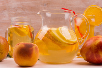 Sparkling White Sangria with oranges, lemon, apple and peach. A pitcher on a rustic wooden background with fruit. Copy space