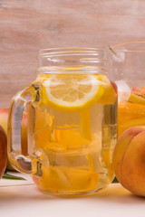 Sparkling White Sangria with oranges, lemon, apple and peach. Mug on a rustic wooden background with fruit.