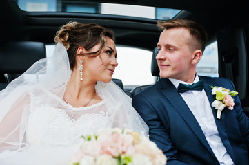 Beautiful wedding couple sitting in the car and looking into each other's eyes.
