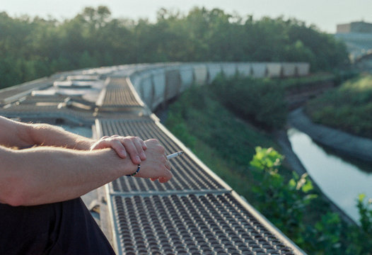 Hands of man smoking a cigarette on top of train