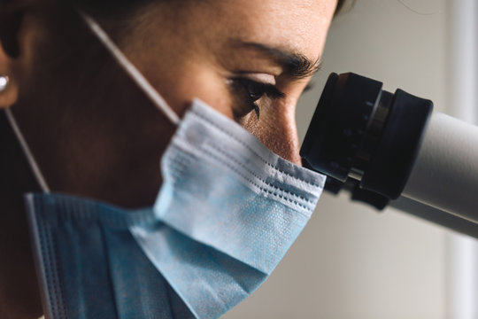 Closeup view of a woman looking through microscope