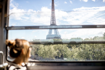 Young woman looking on the Eiffel tower through the train window in Paris. Image focused on the...