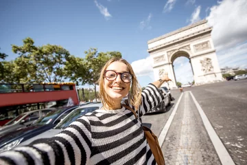 Foto op Plexiglas Young woman tourist making selfie portrait with famous Triumphal Arch on the background in Paris © rh2010