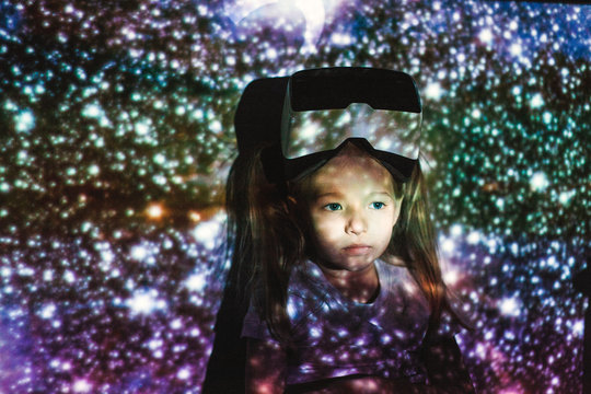Dreamy little girl in multicolored lights with VR headset