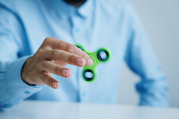 A young guy with a beard on a light background holds a spinner
