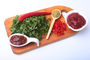 Fresh green cilantro, coriander leaves, tomato paste, chili pepper and spices on a wooden board. Ingredients for meat sauce.