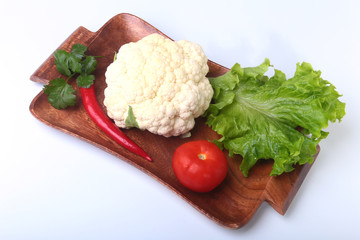 fresh cauliflower, tomato, salad leaves and other vegetables on wooden board. Ready for cooking. Vegetarian food.