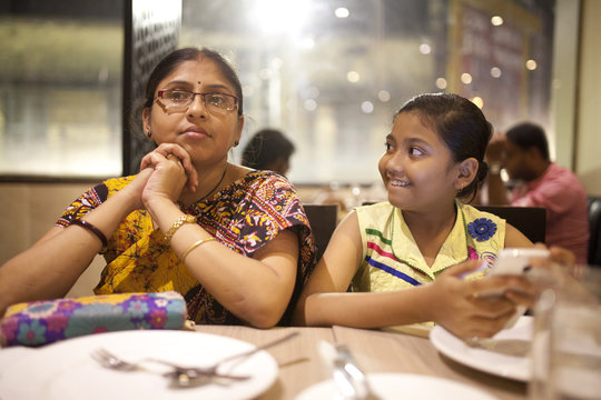 Teenage girl and Adult Woman browsing and texting smartphone in a restaurant