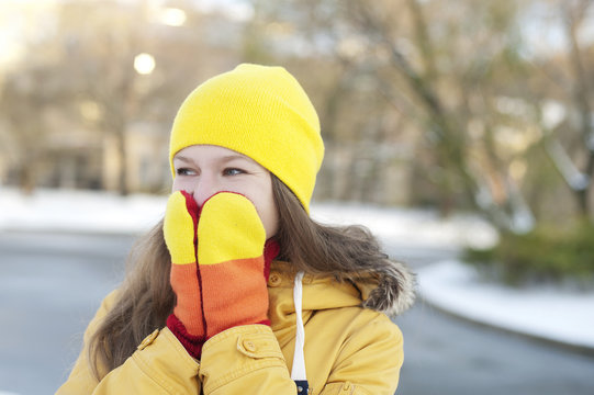 Young woman hiding her smile in mittens