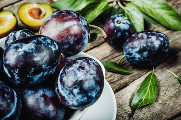 Fresh plums with leaveson a dark wood background. toning. selective focus