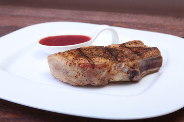 grilled pork chop with Cranberry sauce on plate on wooden board