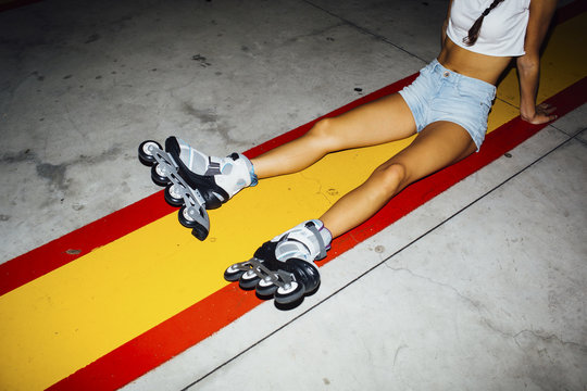 Young woman with roller skates sitting on concrete