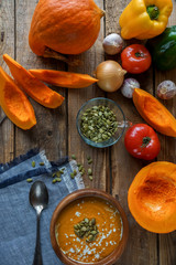 Traditional homemade pumpkin soup with seads, cream and vegetables on rustic wooden table