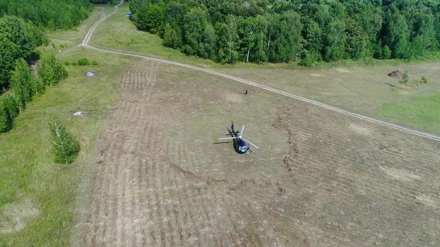 Helicopter lands in a field. Helicopter in the middle of green field prepare to fly. Helicopter arrived on field.