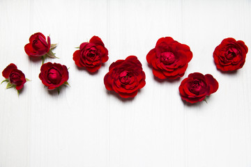 Red roses on a white wooden table. View from above. Flower pattern.