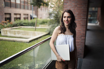 Portrait of young smiling woman holding laptop