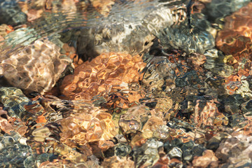 Round stones covered with clear sea water with ripples