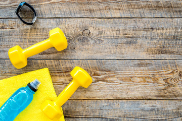 Fitness background. Dumbbells, towel and water on wooden background top view copyspace