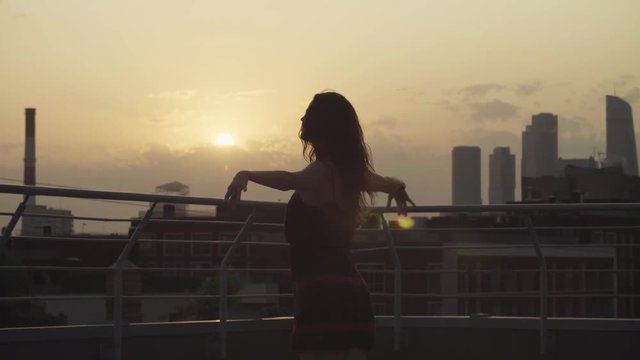 Young woman dancing on the roof on sunset