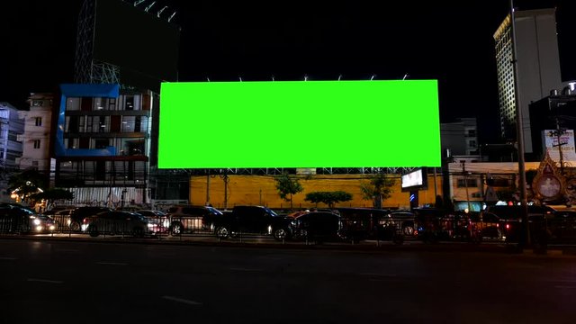 Blank advertising billboard, green screen, beside road with traffic at night, for advertisement, time lapse.