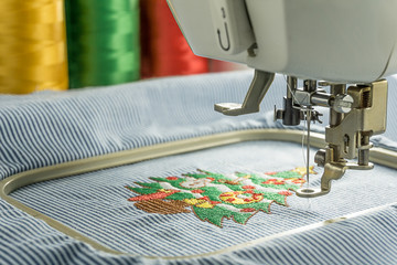 Picture of workspace embroidery machines finsin working cartoon christmas tree on stripes fabric take in medium close up shot
