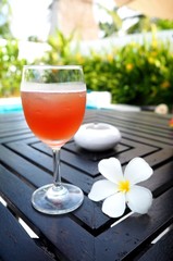 Glass with wine and tropical flower on a table near the pool. It's time to relax. 