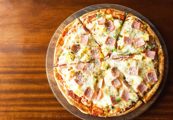 Hawaiian Pizza, pineapple , ham and cheese on wooden table