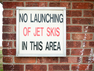 old retro sign lettering on wall saying no launching of jet skies in this area