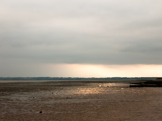 sunsetting in the distance stunning light over mudflats casting glow pretty beach