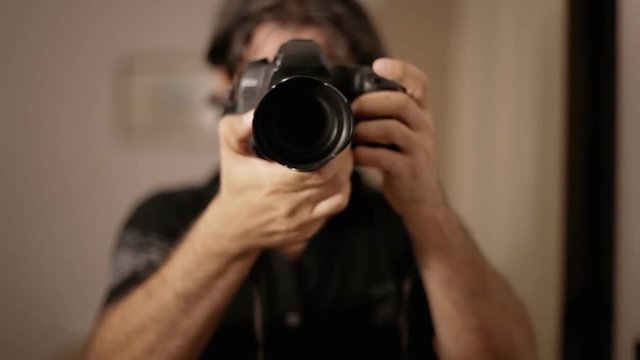 A male photographer shooting portrait pictures of himself in the mirror.
