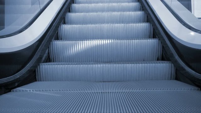 Up and down escalators in public building. Indoors. Blue tone