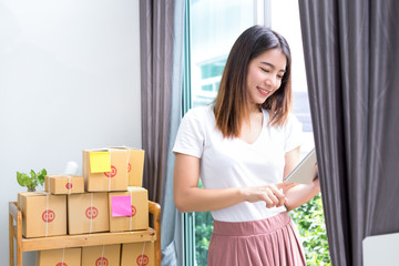 Young asian girl freelancer business private working at home office with holding tablet, laptop, note, packaging delivery online market on purchase or checking orders to customer.