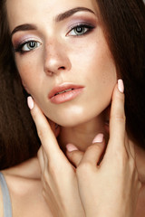 Obraz premium Beauty portrait of young woman touching face with fingers. Brunette girl with long hair and day female makeup
