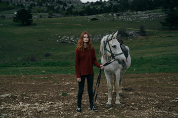 Young beautiful woman holds a horse, nature, mountains, hills