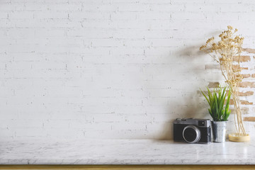 Empty marble top table with vintage camera and houseplant over white brick wall. Copy space for products display montage.