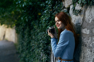 Young beautiful woman is walking along the street with a camera