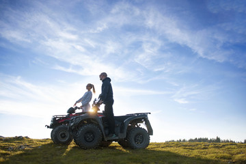 Beautiful couple is watching the sunset from the mountain sitting on quadbike © FS-Stock