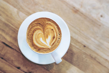 Hot art coffee cappuccino in a cup on wooden table background  with copy space