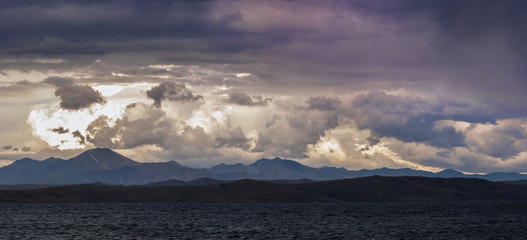 Obraz premium dark fluffy clouds on sky over sea during fiery sunset 