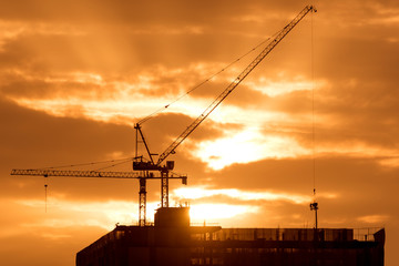 construction crane on site with orange sunset sky background