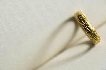 gold ring with shadow heart shape on the book page