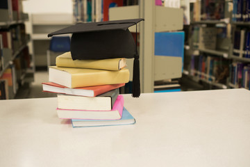 A mortarboard and graduation scroll, tied with red ribbon, stack on book. Education concept.