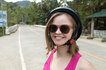 Biker girl in a helmet and glasses with road on background