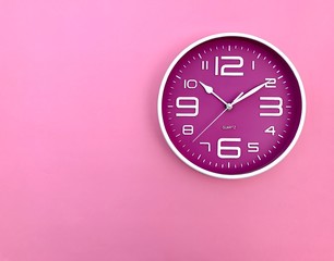 Closeup A deep pink wall clock set on pink background.The concept of" The time is going on."Top view with Copy Space. Selective focus.