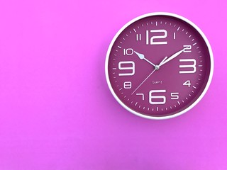 Closeup A deep pink wall clock set on pink background.The concept of" The time is going on."Top view with Copy Space. Selective focus.