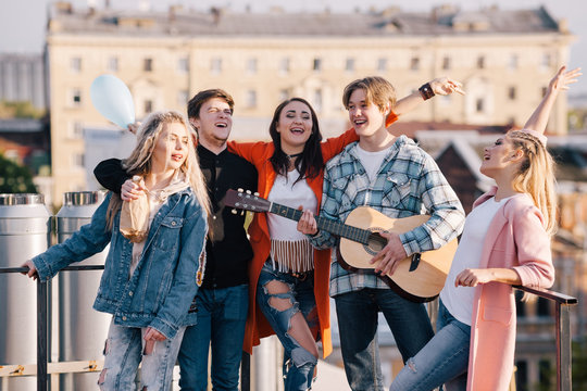 Student music group at festival. Creative get-together outdoors, young company of people with guitar