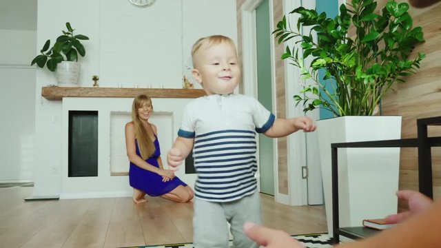 Carefree ittle boy the baby is making his first steps. Comes from mom to dad, laughs