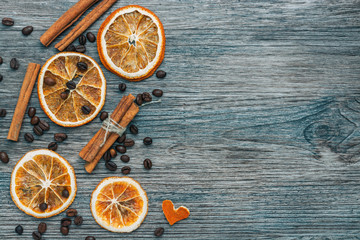 Coffee beans,cinnamon and dried orange on wooden surface ,blue toning,top view. Heart of orange peel.