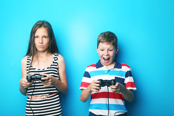 Young boy and girl with joysticks on blue background © 5second